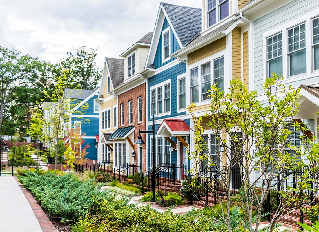Home and Condo Owner Association Insurance - Row of Colorful, Red, Yellow, Blue, White, and Green Painted Residential Townhouses With Brick Patio in the Summer